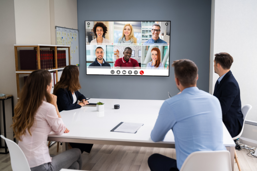 Employees in a brightly lit conference room conducting a virtual meeting using audio-video solutions.
