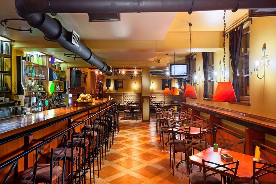 Long view of bar and restaurant seating with warm accents and pub atmosphere.