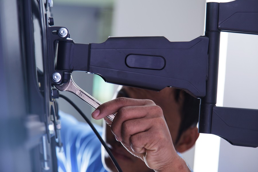 Close up shot of an installer putting up a motorized television mount for business AV purposes.